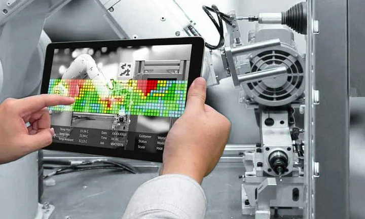 Engineer inspecting an industrial machine on a tablet